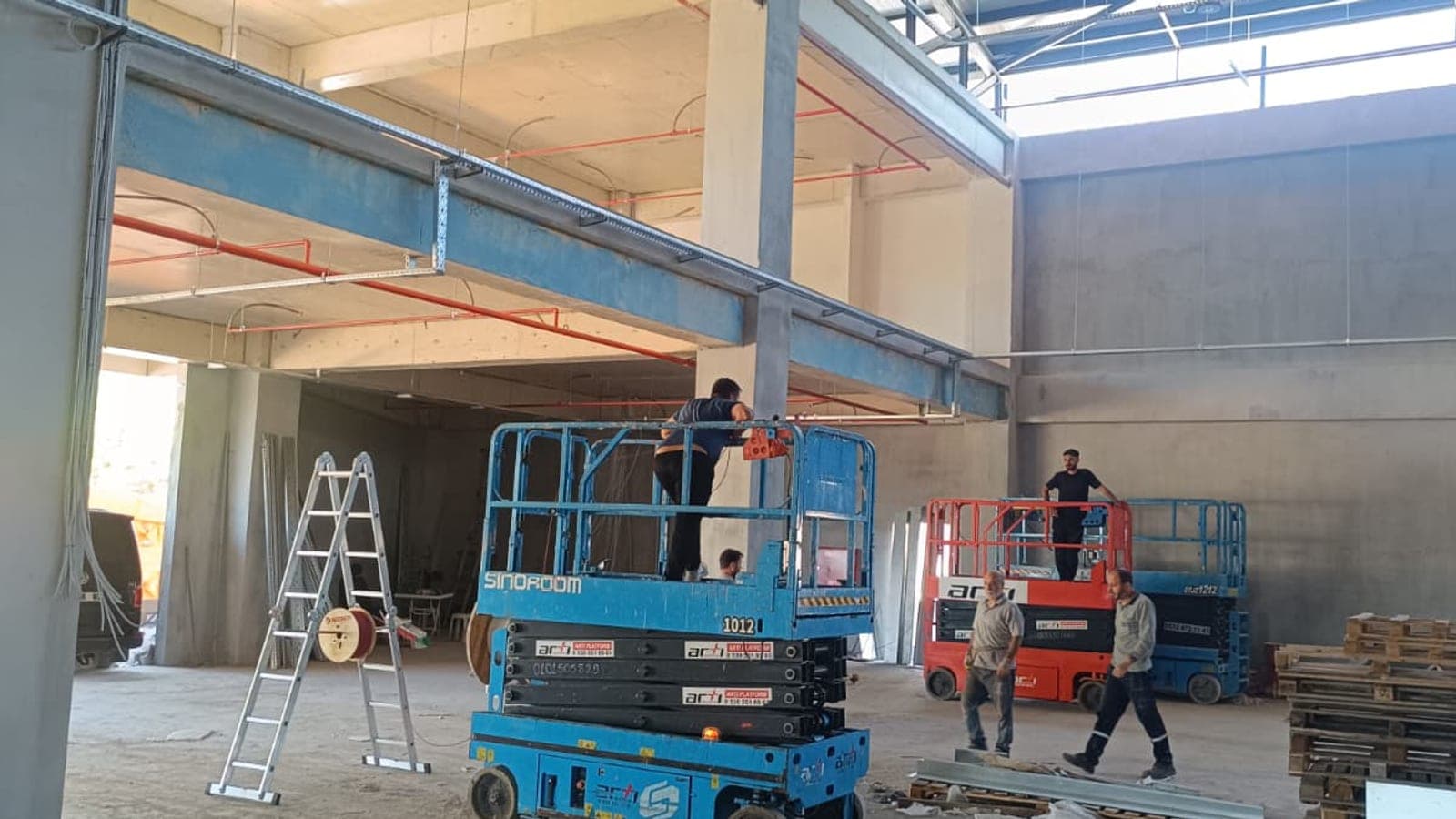 Yüksek tavanlı depo binasında iki akülü makaslı platformla paralel yürütülen sprinkler hattı montajı